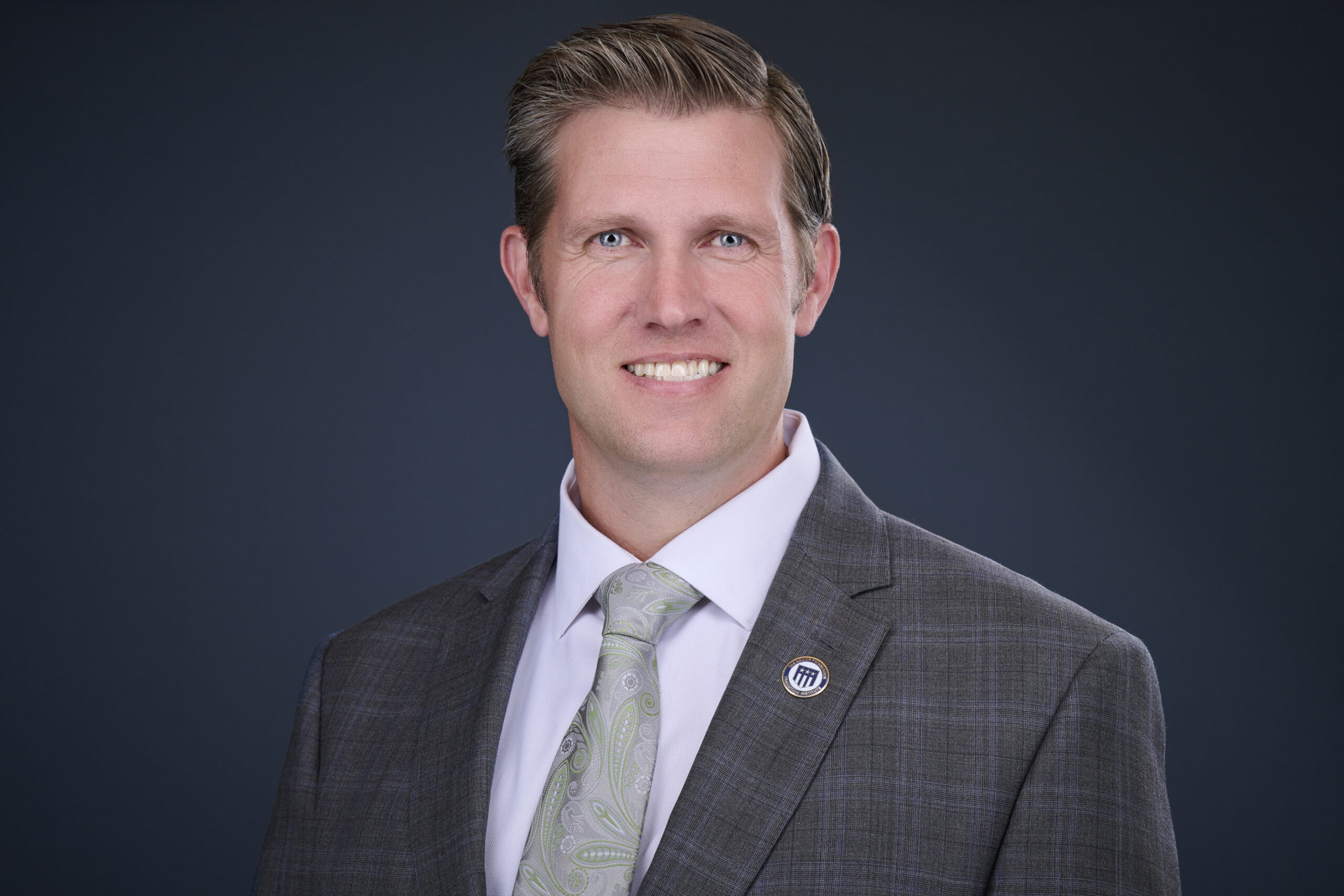Portrait of Burton Nyhus wearing a grey suit and tie.